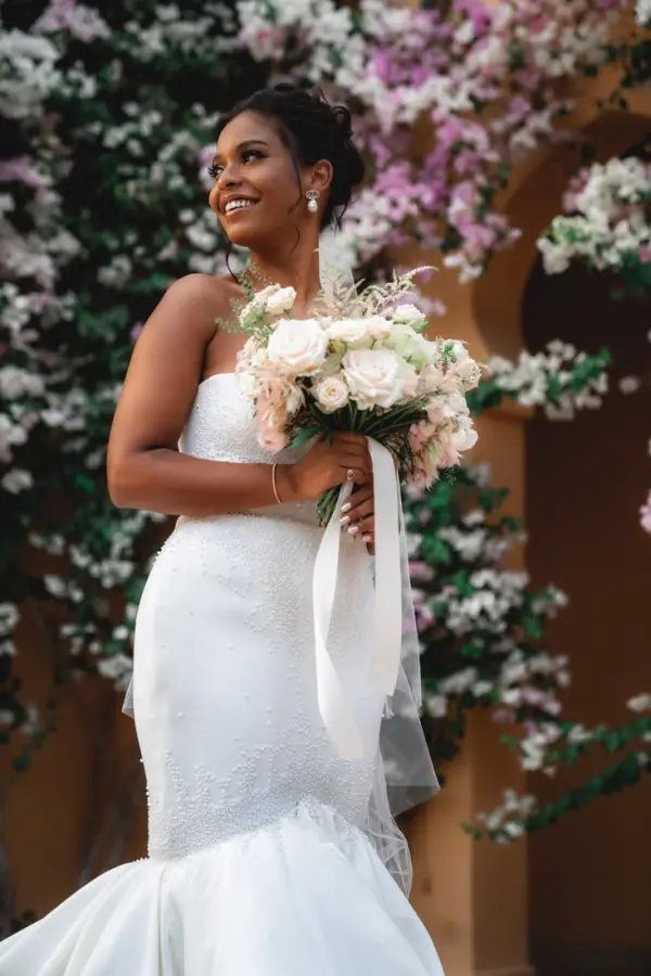 Bride smiling with her bouquet in front of a bougainvillea wall - wedding photographer Marrakech
