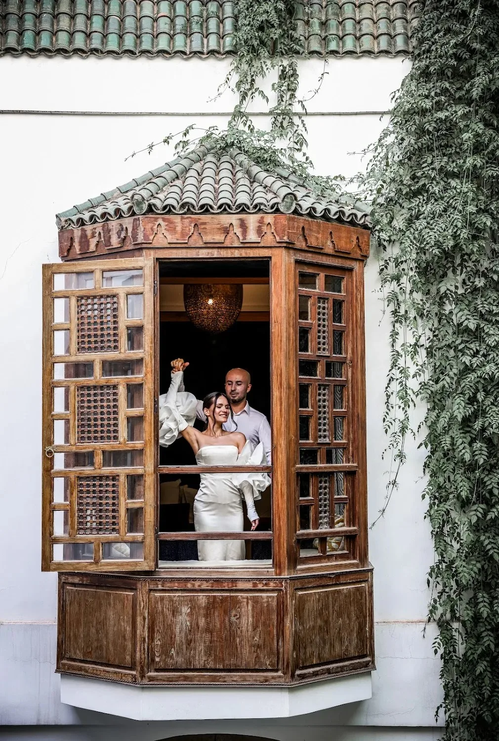 Bride and groom framed in a carved wooden riad window - wedding photographer Marrakech
